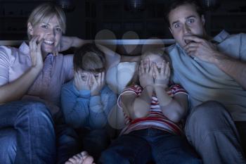 Family Watching Scary Programme On TV Sitting On Sofa Together