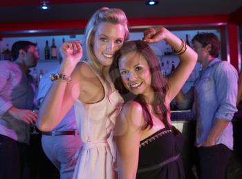 Two Young Women Having Fun In Busy Bar