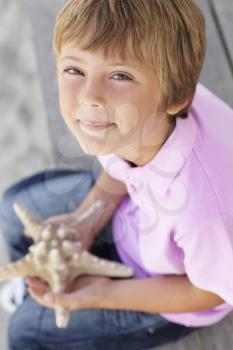 Young boy outdoors holding starfish