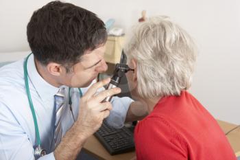 British doctor examining senior woman's ear