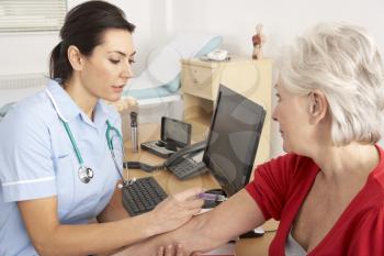 British nurse giving injection to senior woman