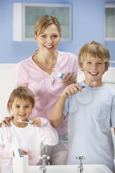 Mother and children cleaning teeth in bathroom