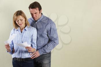 Studio Shot Of Middle Aged Couple Looking at Bills