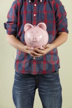 Cropped Studio Shot Of Young Boy Holding Pink Piggy Bank