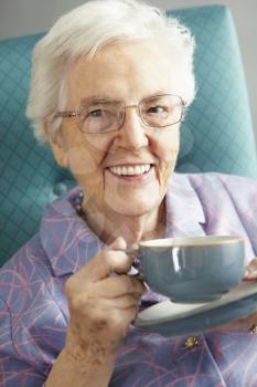Senior Woman Relaxing In Chair With Hot Drink