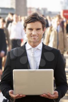 Male commuter in crowd using laptop
