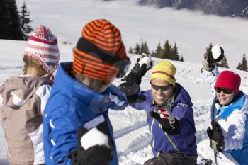 Family Having Snowball Fight On Ski Holiday In Mountains