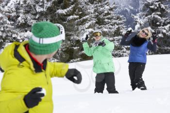 Group Of Young Friends Having Snowball Fight On Ski Holiday In Mountains
