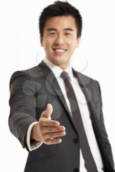 Studio Portrait Of Chinese Businessman Reaching Out To Shake Hands