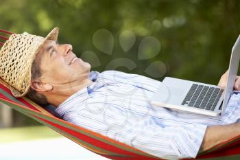 Senior Man Relaxing In Hammock With Laptop