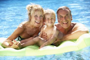 Grandparents And Grandson Having Fun In Swimming Pool