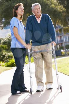 Carer Helping Senior Man With Walking Frame