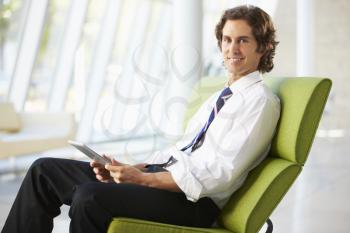 Businessman Sitting On Sofa In Office Using Digital Tablet