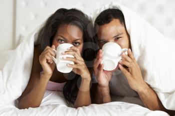 Couple Relaxing In Bed With Hot Drink