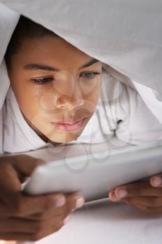 Boy Using Digital Tablet Under Duvet