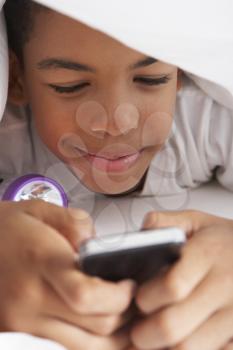 Boy Using Mobile Phone Under Duvet
