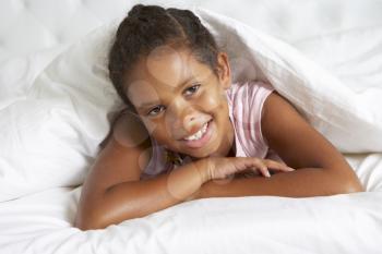 Young Girl Hiding Under Duvet In Bed