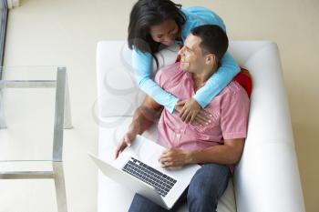 Overhead View Of Couple Relaxing On Sofa Using Laptop