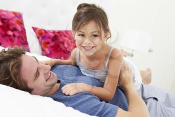 Father And Daughter Lying In Bed Together