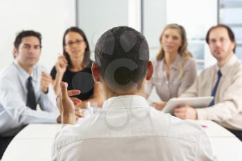View From Behind As CEO Addresses Meeting In Boardroom