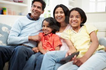 Indian Family Sitting On Sofa Watching TV Together