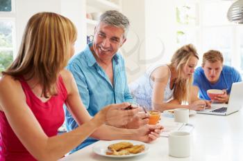 Teenage Family Having Breakfast In Kitchen With Laptop