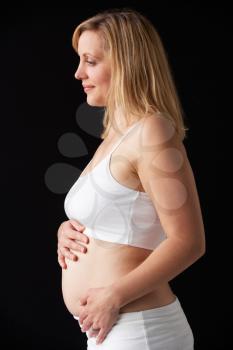 Portrait Of 4 months Pregnant Woman Wearing White On Black Background