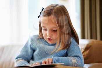 Young Girl Reading Story At Home