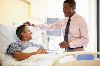 Doctor Talking To Male Patient In Hospital Room