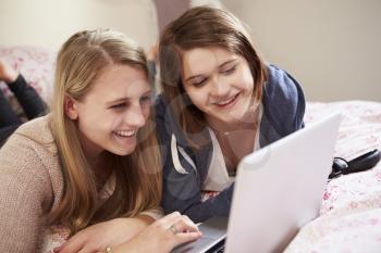 Two Teenage Girls Using Laptop In Bedroom