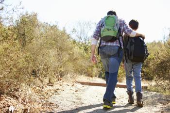 Rear View Of Father And Son Hiking In Countryside