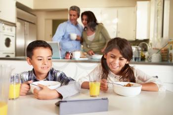 Hispanic Family Eating Breakfast Using Digital Devices