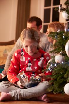 Girl Unwrapping Gifts By Christmas Tree
