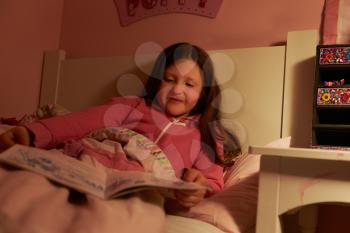 Young Girl Reading Book In Bed At Night