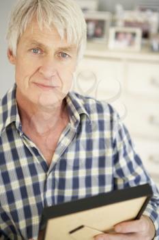 Senior man with photographs at home