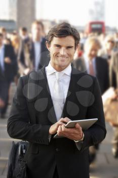 Male commuter in crowd using tablet