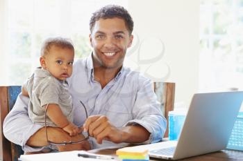 Father With Baby Working In Office At Home