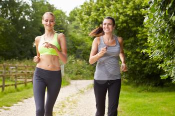 Two Female Friends On Run In Countryside Together