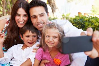 Family Sitting On Seat In Garden At Home Taking Selfie