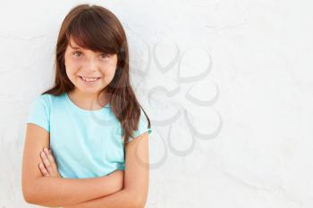 Smiling Young Girl Standing Outdoors Against White Wall