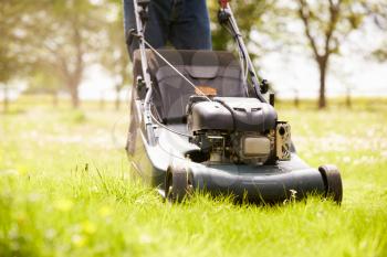 Close Up Of Man Working In Garden Cutting Grass With Mower