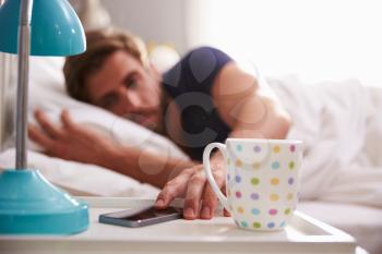 Sleeping Man Being Woken By Mobile Phone In Bedroom