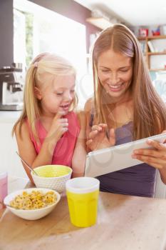 Mother And Daughter Using Digital Tablet At Breakfast Table