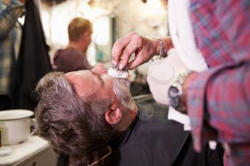 Male Barber Preparing Client For Shave In Shop