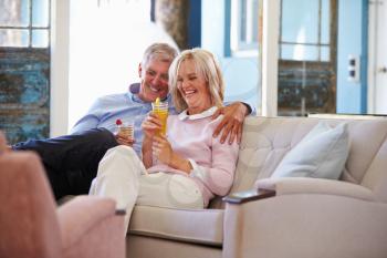Mature Couple At Home Relaxing In Lounge With Cold Drinks