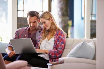 Couple At Home In Lounge Using Laptop Computer