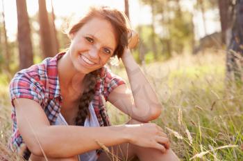 Portrait Of Smiling Young Woman Sitting In Countryside