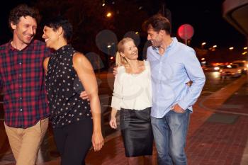 Two couples walking through town together at night