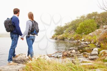 Young couple standing by a lake admiring the view