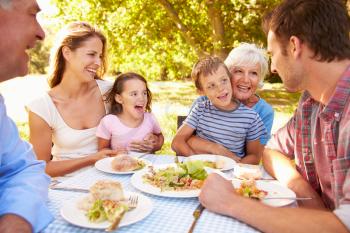 Multi-generation family eating together outdoors